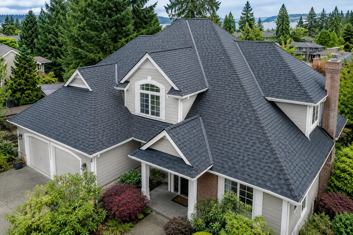 Aerial view of a two-story Northwest home with a complex charcoal shingle roof of hips, valleys, and dormers