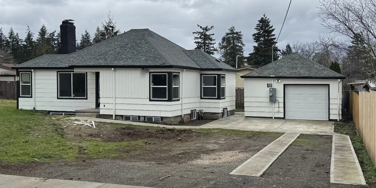 The home and detached garage after, with new charcoal-gray roofs