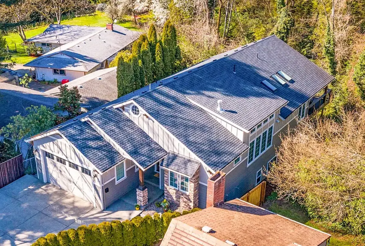 Aerial view of a craftsman-style home in Vancouver, WA with a new charcoal-gray shingle roof, front gables over the garage and porch, skylights, and a brick chimney
