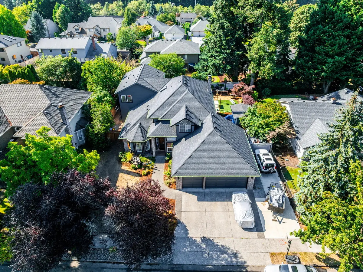 Aerial view of a two-story gray home in Vancouver, WA with a new charcoal-gray shingle roof, gable dormers, and a three-car garage