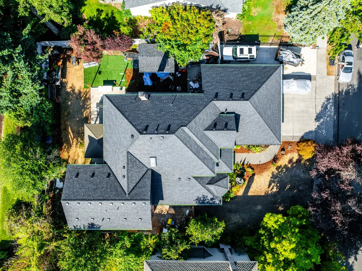Straight-down drone view of the full new roof, including hips, valleys, dormers, and the chimney