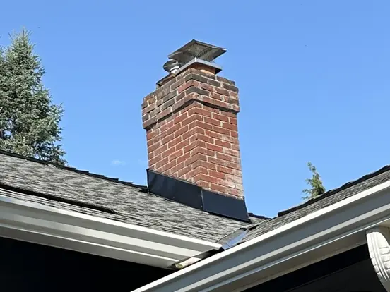 Brick chimney with new black flashing on a shingle roof
